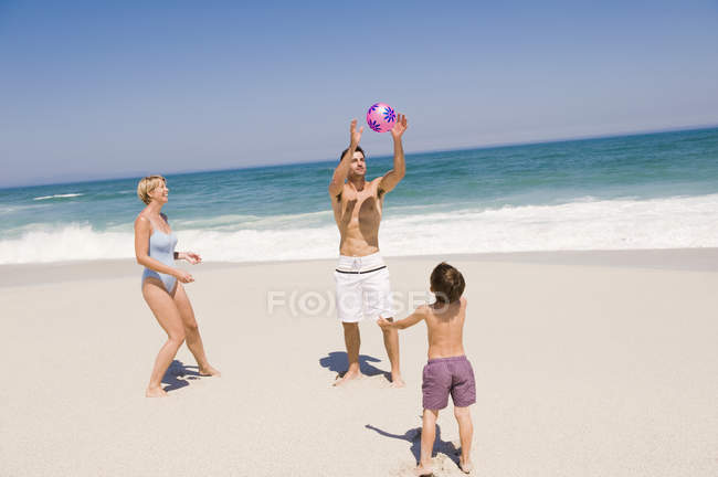 Семья играет с пляжным мячом на песке — стоковое фото