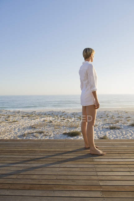 Жінка з коротким волоссям, стоячи на прогулянці на морському узбережжі і дивлячись на погляд — стокове фото