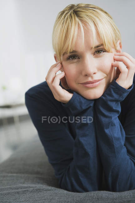 Portrait of young woman with head in hands looking at camera — Stock Photo