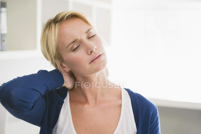 Втомлена жінка з закритими очима торкається шиї — стокове фото