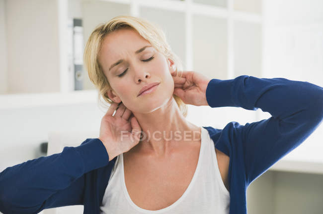 Tired woman with eyes closed touching neck — Stock Photo