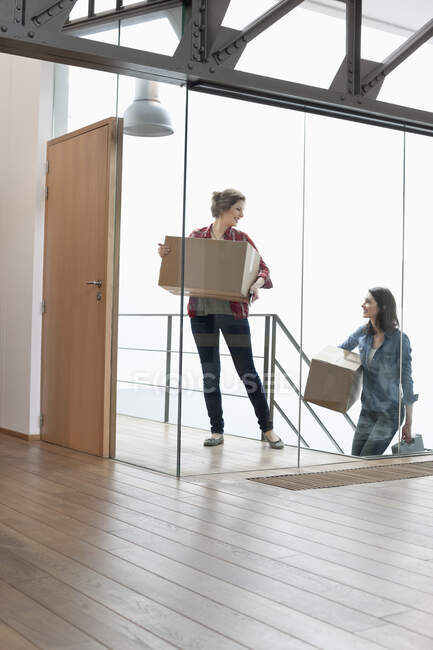Two female friends carrying cardboard boxes at home — Stock Photo