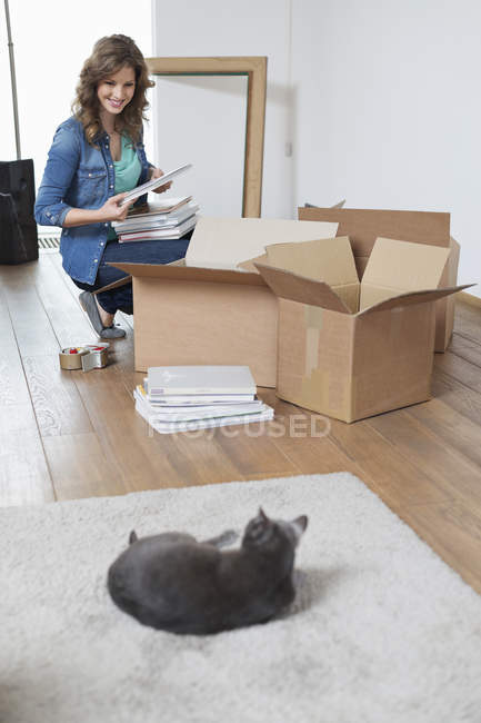 Mujer mirando a gato en apartamento y sonriendo - foto de stock