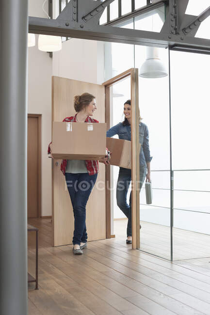 Female friends carrying cardboard boxes at home — Stock Photo