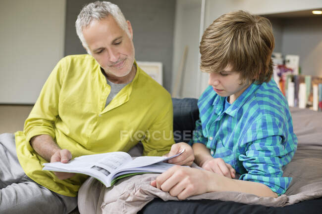Хлопчик-підліток вчиться з батьком вдома — стокове фото