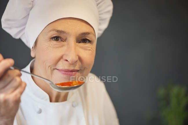 Retrato de mulher em traje chef degustação de molho de tomate — Fotografia de Stock