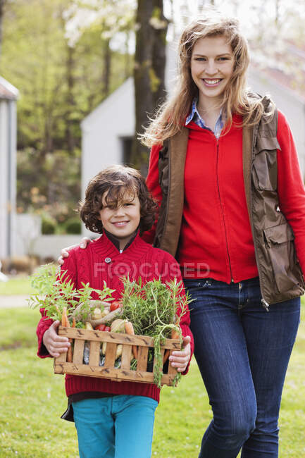 Madre e figlio con una cassa di verdure fatte in casa — Foto stock