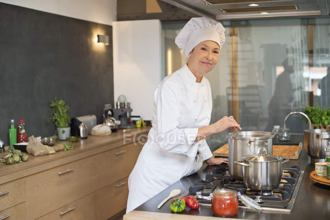 Mulher em traje de chef cozinhar comida na cozinha — Fotografia de Stock