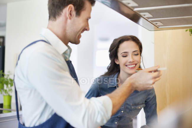 Smiling couple tasting food together — Stock Photo