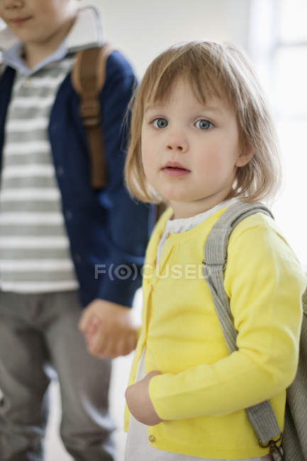 Portrait of little schoolgirl and schoolboy standing holding hands — Stock Photo