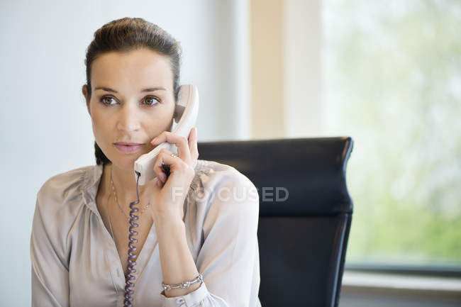 Empresária falando no telefone fixo no escritório — Fotografia de Stock