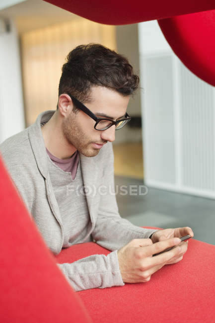 Молодой бизнесмен текстовые сообщения в офисе — стоковое фото