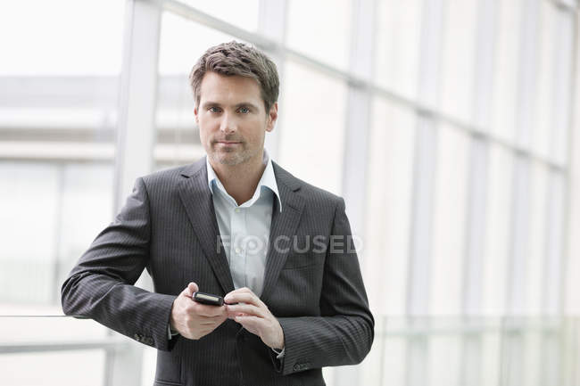 Porträt einer Geschäftsfrau per SMS auf dem Handy im Büro — Stockfoto