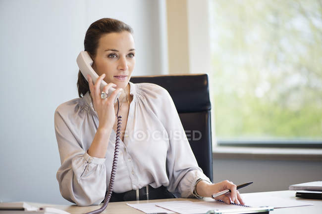 Donna d'affari che parla al telefono fisso in ufficio — Foto stock