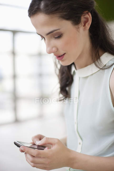 Bruna giovane donna utilizzando smartphone — Foto stock
