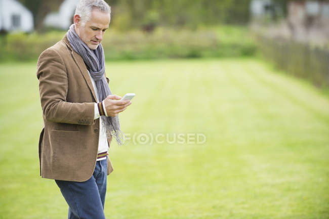 Uomo elegante che utilizza il telefono cellulare nel parco — Foto stock