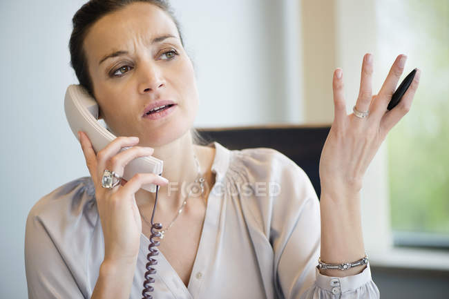 Деловая женщина разговаривает по стационарному телефону в офисе — стоковое фото