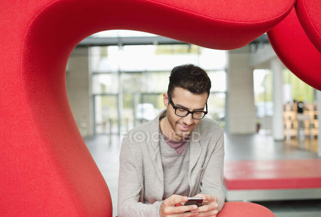 Empresario mensajería de texto y sonriendo en una oficina - foto de stock