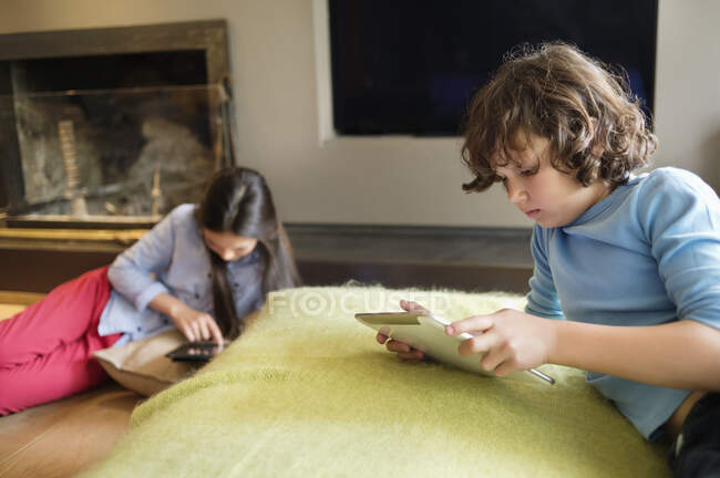 Ragazzo e una ragazza utilizzando gadget elettronici a casa — Foto stock