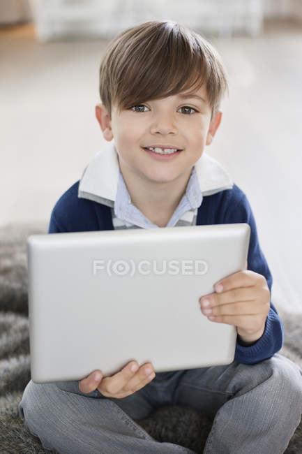 Retrato de menino sorridente segurando tablet digital no apartamento moderno — Fotografia de Stock