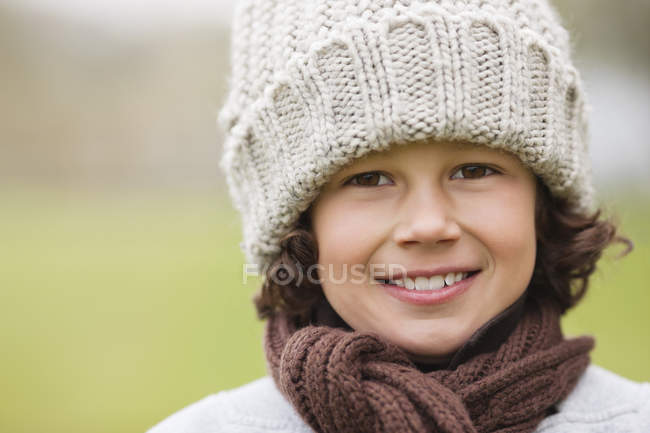 Retrato de menino sorridente usando chapéu de malha ao ar livre — Fotografia de Stock