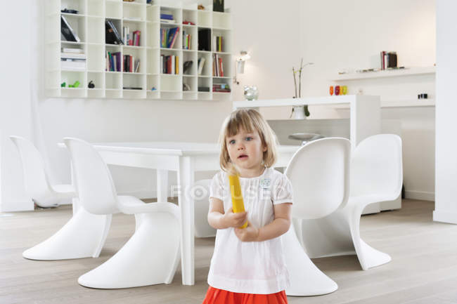 Симпатичная маленькая девочка держит большой карандаш в современной квартире — стоковое фото