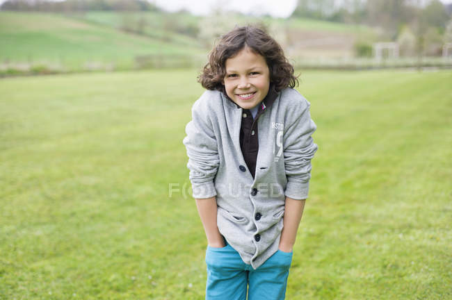 Portrait of cheerful boy standing in green autumn field — Stock Photo