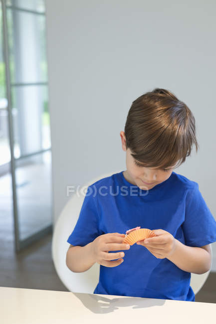 Little boy holding cupcake at kitchen table — Stock Photo