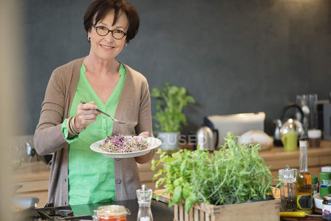 Portrait of senior woman tasting food in kitchen — Stock Photo