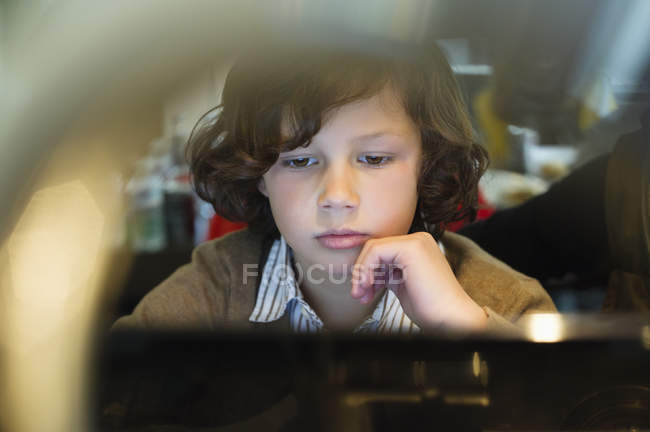 Primer plano del niño enfocado usando el ordenador portátil - foto de stock