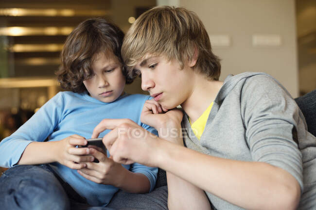 Хлопчик-підліток з братом використовує мобільний телефон — стокове фото