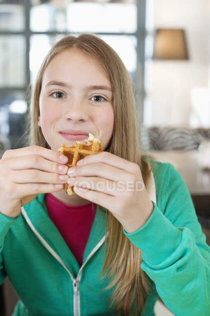 Retrato de una adolescente sonriente comiendo waffle - foto de stock