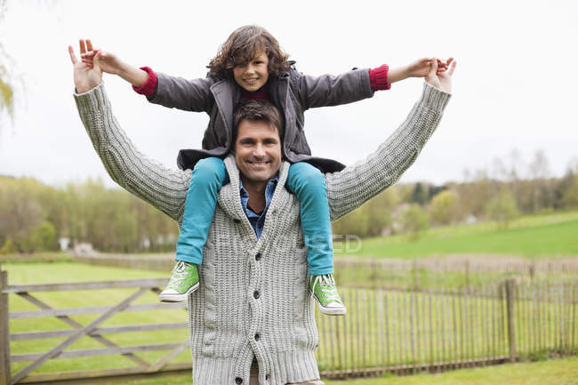 Mann trägt lächelnden Sohn auf Schultern im Freien — Stockfoto