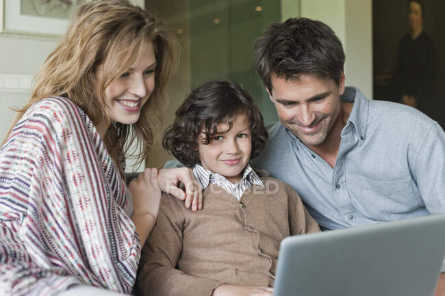 Хлопчик використовує ноутбук з батьками вдома — стокове фото