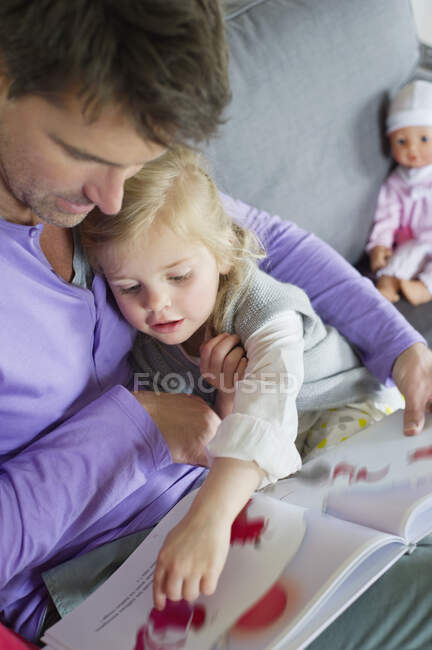 Chica estudiando con su padre en casa - foto de stock