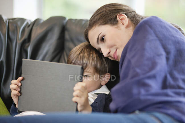 Жінка дивиться на сина за допомогою цифрового планшета — стокове фото