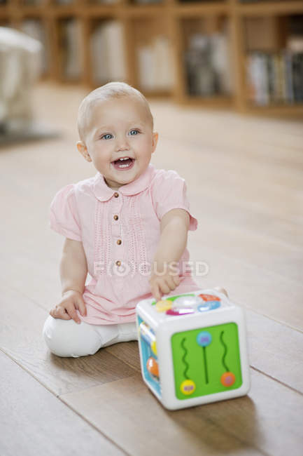 Bambina che gioca con il blocco musicale giocattolo sul pavimento a casa — Foto stock