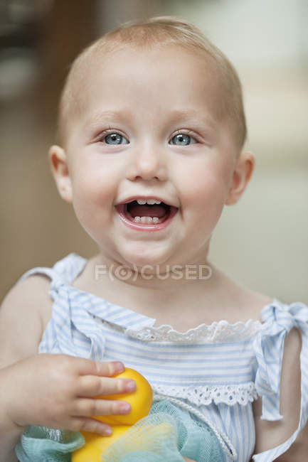 Gros plan de bébé fille jouant avec jouet et riant — Photo de stock