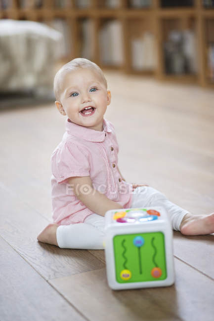 Baby girl playing with musical block toy on floor at home — Stock Photo