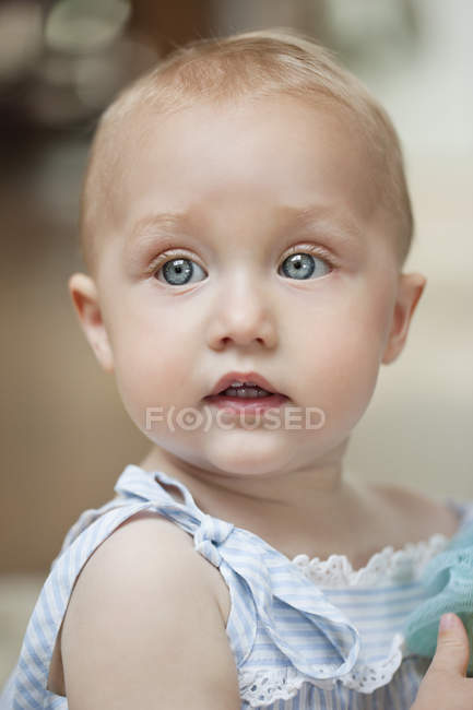 Gros plan de bébé fille aux yeux bleus regardant ailleurs — Photo de stock