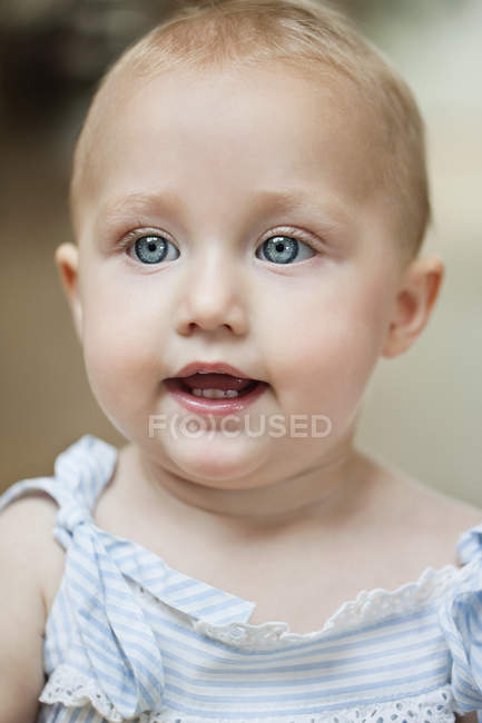 Gros plan de bébé fille aux yeux bleus regardant ailleurs — Photo de stock