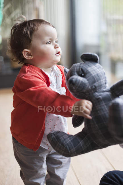 Mignon bébé fille tenant un ours en peluche — Photo de stock