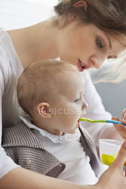 Primer plano de mujer alimentación lindo bebé hija - foto de stock
