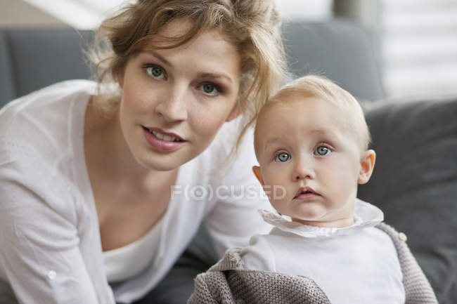 Retrato de mulher jovem com filha de bebê curioso bonito em casa — Fotografia de Stock