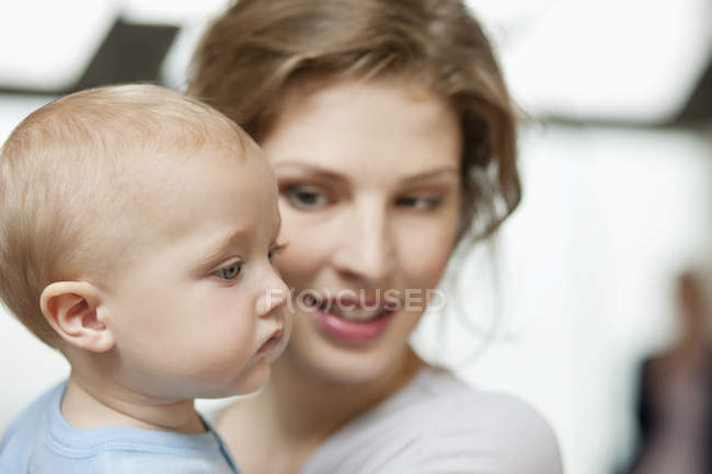 Gros plan de la femme souriante regardant bébé fille curieuse mignonne — Photo de stock