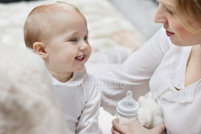 Frau mit Babyflasche spielt mit lächelnder Tochter — Stockfoto