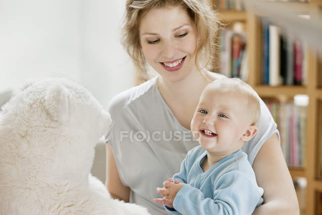 Smiling woman playing with happy baby daughter at home — Stock Photo