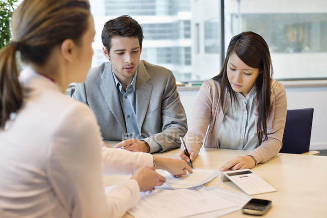 Couple signing documents with business executive — Stock Photo