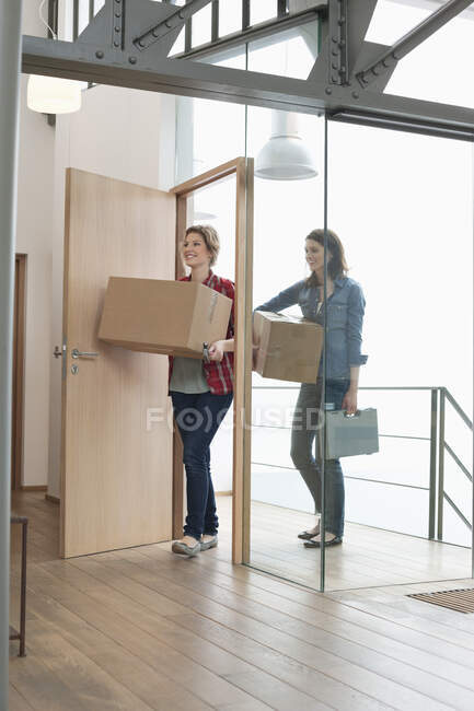 Amigos do sexo feminino carregando caixas de papelão em casa — Fotografia de Stock