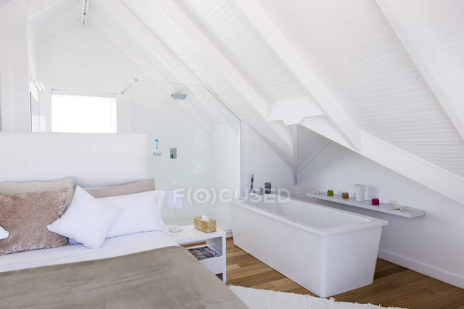 Interior of stylish light bedroom with bathtub — Stock Photo
